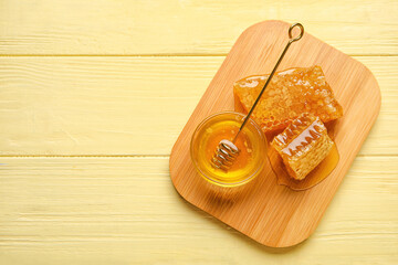 Bowl of honey and combs on yellow wooden background