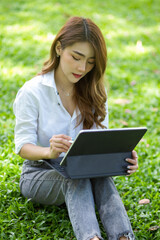 Charming asian female sitting at the yard using portable tablet