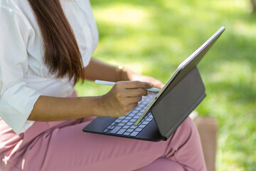 Naklejka premium Cropped image of a young woman in a park using a tablet
