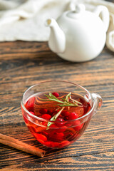 Cup of tasty cranberry tea and cinnamon on wooden background