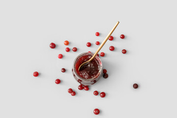 Jar with tasty cranberry jam and berries on white background