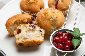 Plate with tasty cranberry muffins on table, closeup