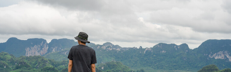 web banner man relax after hiking to top of mountain in raining season travel