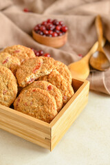 Wooden box with fresh cranberry cookies on light background, closeup
