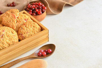 Wooden box with fresh cranberry cookies and berries on light background, closeup