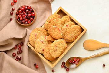 Wooden box with fresh cranberry cookies and berries on light background