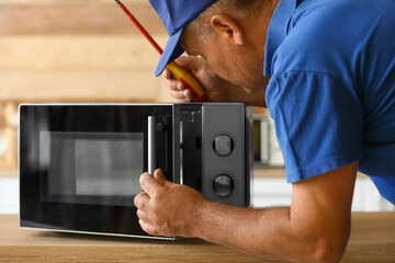 Male worker repairing microwave oven in kitchen