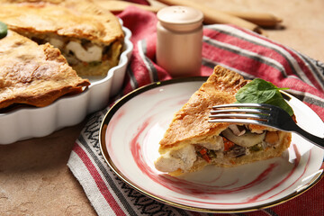 Plate with piece of tasty chicken pot pie on beige background