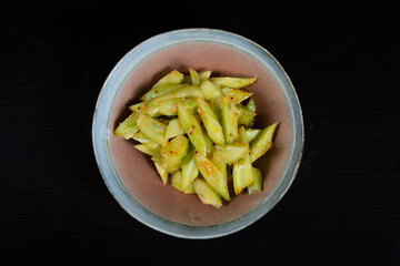 Salad with chopped cucumbers in garlic sauce on a black background