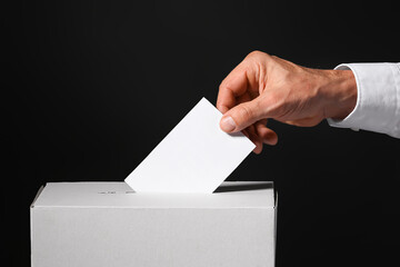 Voting man near ballot box on dark background