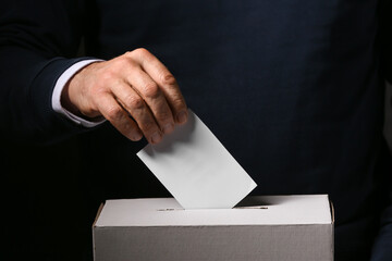 Voting man near ballot box on dark background