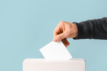 Voting man near ballot box on color background
