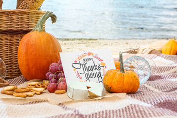 Pumpkin, cheese and card with text HAPPY THANKSGIVING on beach