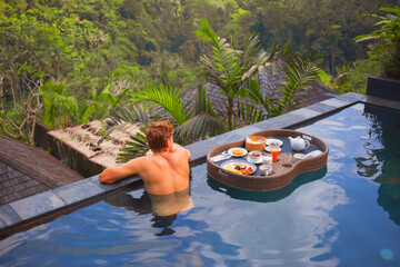 Floating food tray. Man at pool side above jungle