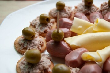 Cocktail party food. Close up of ham, cheese and cookies with tuna on white dish