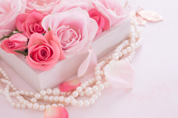 箱に詰めたピンクの薔薇の花とアクセサリー