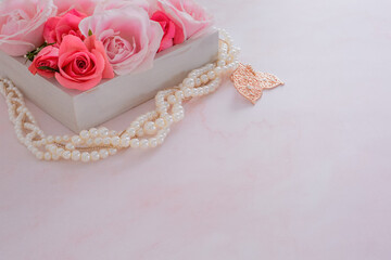 箱に詰めたピンクの薔薇の花とアクセサリー