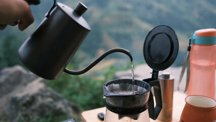 Coffee drip while camping in forest with sunshine. Coffee maker outdoor, campsite morning picnic...