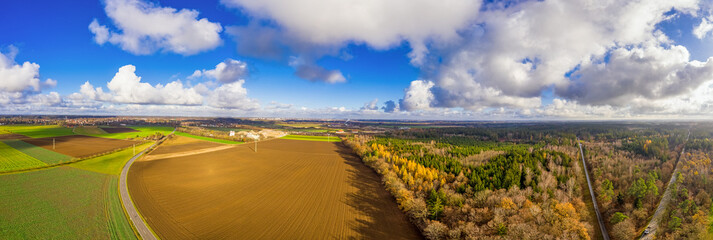 Autumn landscape from a aerial view. Blue sky with puffy clouds and orange colored fall fields with...