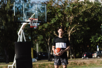 Sports and recreation concept a young male basketball player holding a basketball alone in the basketball court background