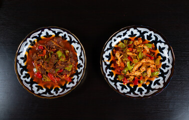 Two plates with oriental cuisine dishes, meat and chicken with vegetables