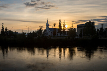Silhouetted cityscape downtown Fairbanks over Chena river at summer sunset