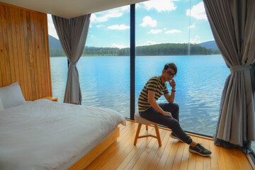 Man enjoying at bed room of wooden lake house