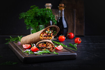 Burritos wraps with beef and vegetables on  dark wooden background. Beef burrito, mexican food.
