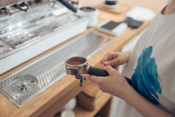 Fototapeta na wymiar Female barista hands holding portafilter with fresh ground coffee