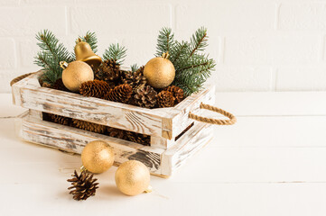 decorative box made of wood made with their own hands with New Year's gold balls and cones spruce on a wooden table.