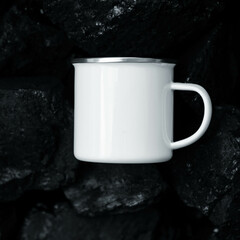 Mockup of a white enameled camping mug on rocks, black stones. an iron mug for traveling.
