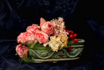 Faded pink and white roses and rose berries with black background