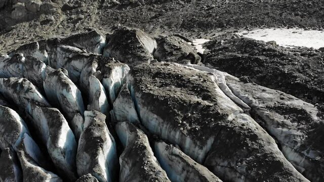 Aerial flyover over the crevasses of the Tiefen glacier in Uri, Switzerland, with rotating view of the glacial lake and waterfall