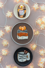 Three plates: black, brown and white with handmade gingerbread. Photographed a minimalistic composition from above on a brown background with christmas stars 