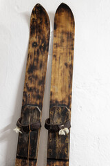 Vintage wooden skis stand near a white wall