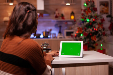 Young person watching green screen technology on tablet in kitchen at home. Caucasian woman using digital chroma key concept for background template, mockup gadget app on virtual display