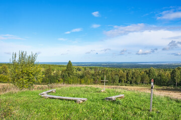 Wooden benches with a cross at a resting place on a footpath with beautiful views