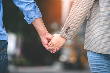 Close-up photo of romantic couple walking hand in hand outdoors