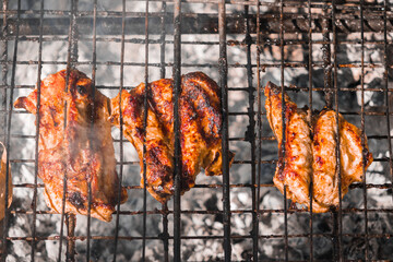 Cooked ruddy chicken meat on a wire rack over a fire. Street food. Picnic in nature. High quality photo