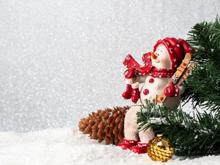 A snowman with skis sits on a pine cone.