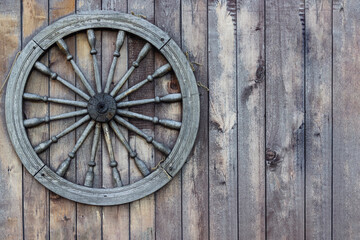 wheel of an old wooden cart on a wooden wall, use as a background