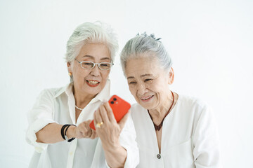 笑顔でスマートフォンの画面を見るシニア女性たち