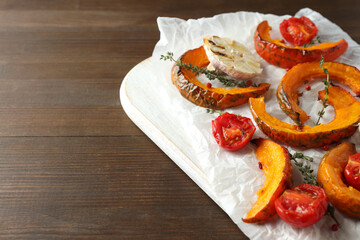 Board with baked pumpkin and spices on wooden background