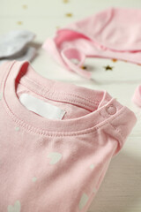 Concept of female baby clothes on white wooden background