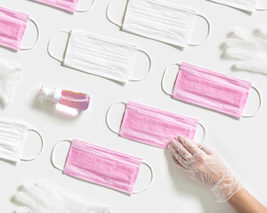 Medical pattern with personal protective equipment masks, hand sanitizer gel, rubber gloves. Woman hand take disposable medical mask