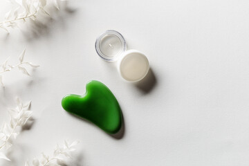 Gouache scrapes from green jade and moisturizing gel, floral decorated. Natural gem stone massager © yrabota
