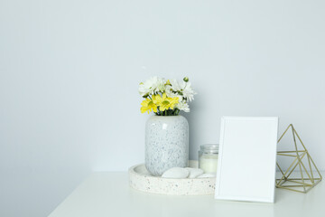 Beautiful composition with chrysanthemums and empty photo frame on white table