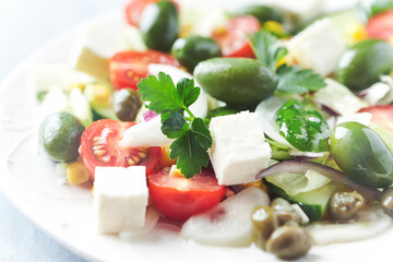 Healthy Salad with Feta Cheese, Green Olives, Baby Spinach, Cucumber, Cherry Tomatoes and Capers. Bright background. Close up. 