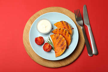 Concept of tasty food with baked pumpkin on red background