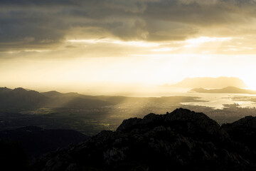 View from above, stunning sunrise during a cloudy day with the city of Olbia, the homonymous gulf and Tavolara island in the distance. Panoramic view from Monte Pino, Sardinia, Italy.